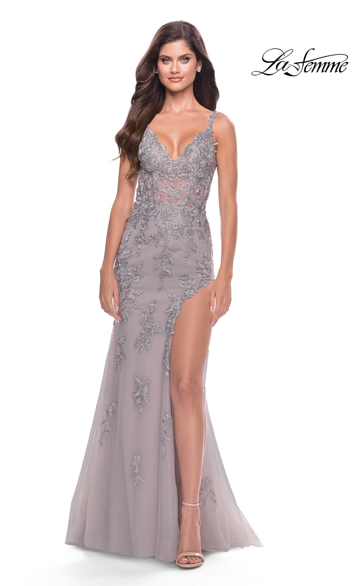A woman stands against a white background wearing a La Femme Long Lace Prom Dress with a sheer bodice, sleeveless design, deep V-neckline, and high slit.